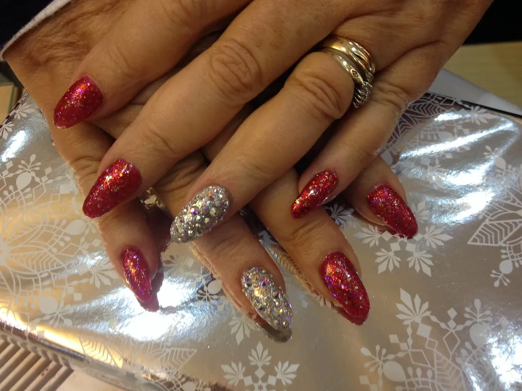 Almond shaped nails with red glitter and Swarovski ring fingers