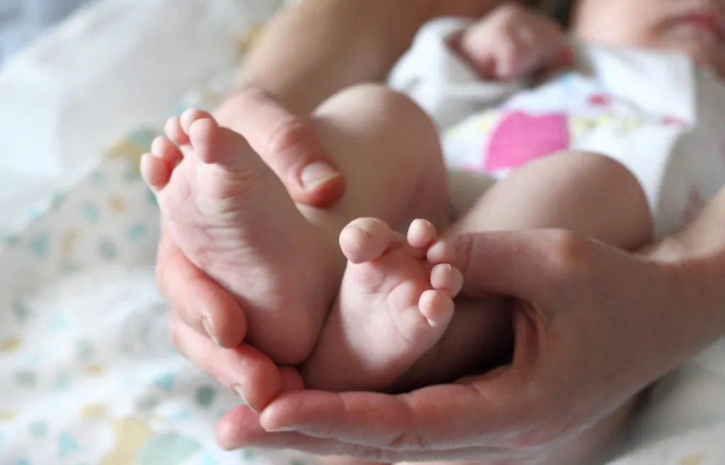 Newborn baby feet in large hands