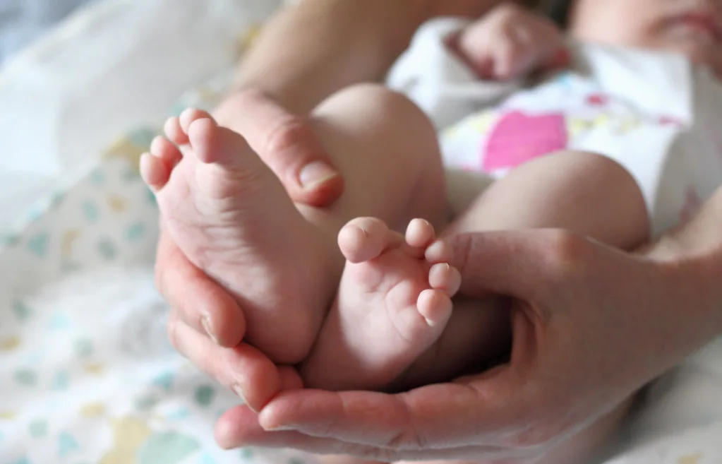 Newborn baby feet in large hands