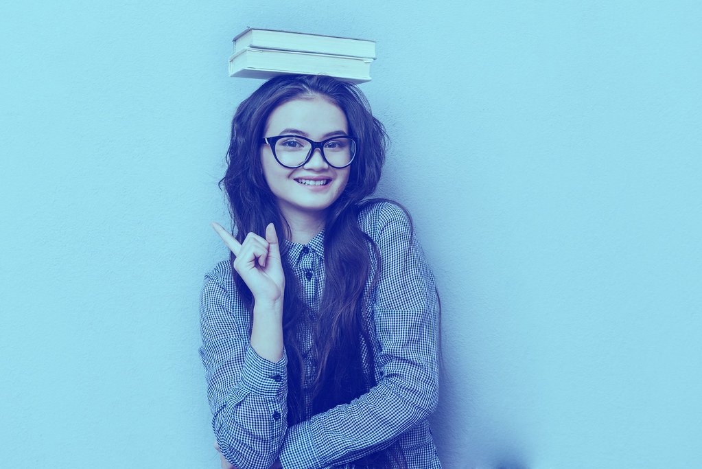 Young asian woman with books on head