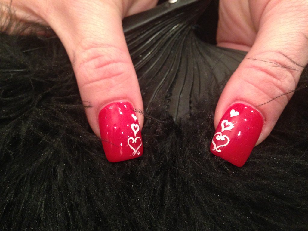 Acrylic nails with red gelish gel polish and freehand nail art with valentine love hearts