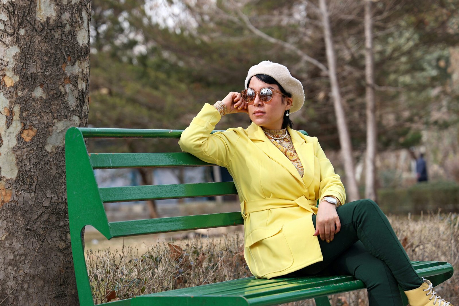 Woman in yellow jacket sits on a park bench