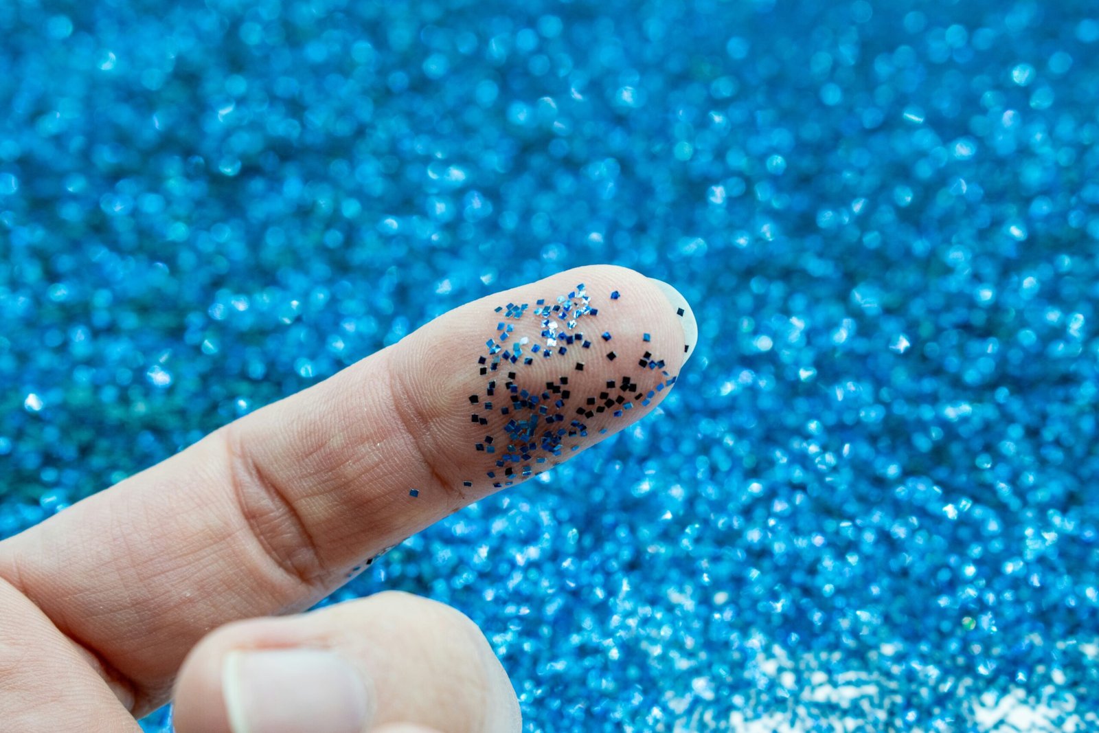 a finger with blue glitter on it and a blue background