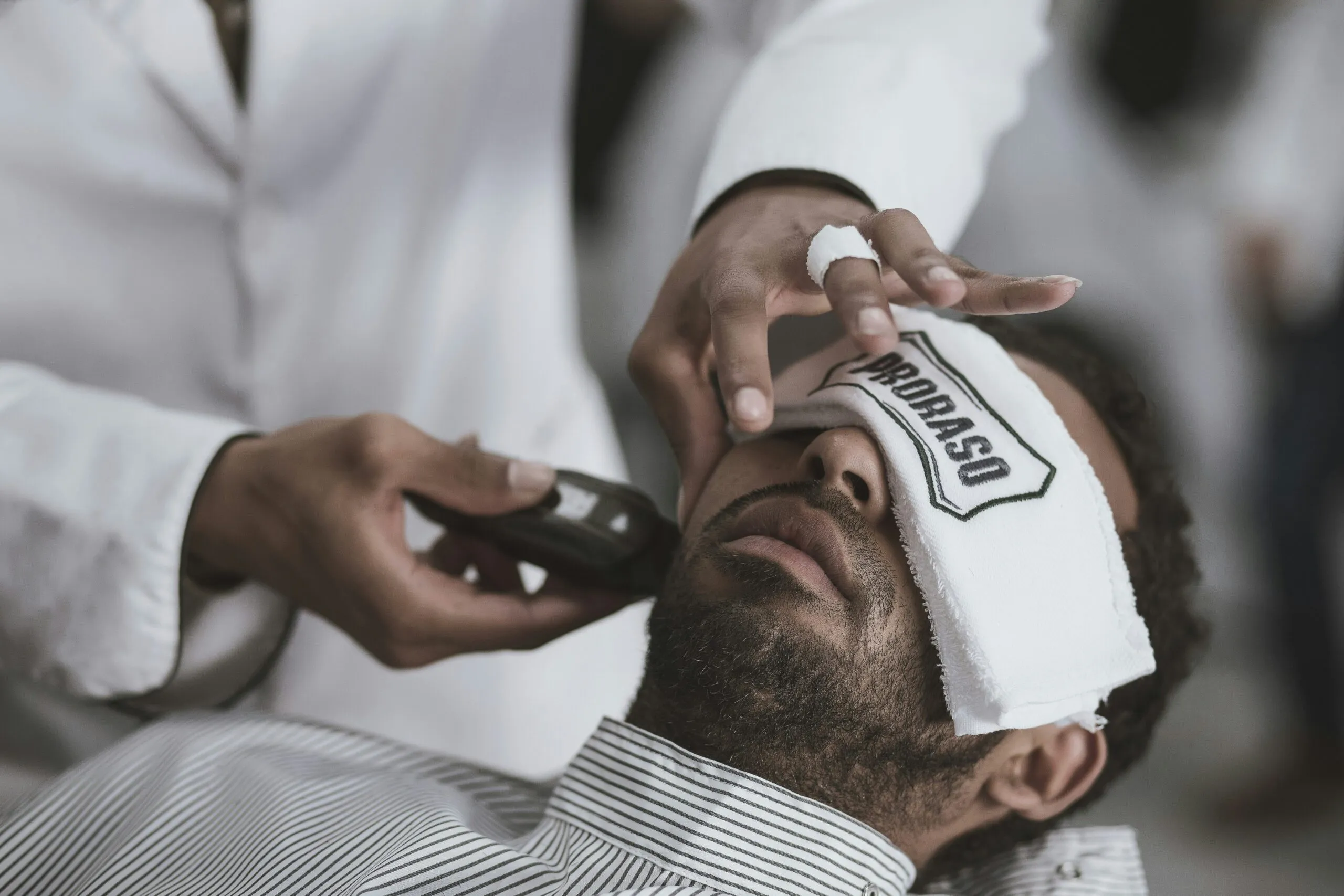man shaving lying man