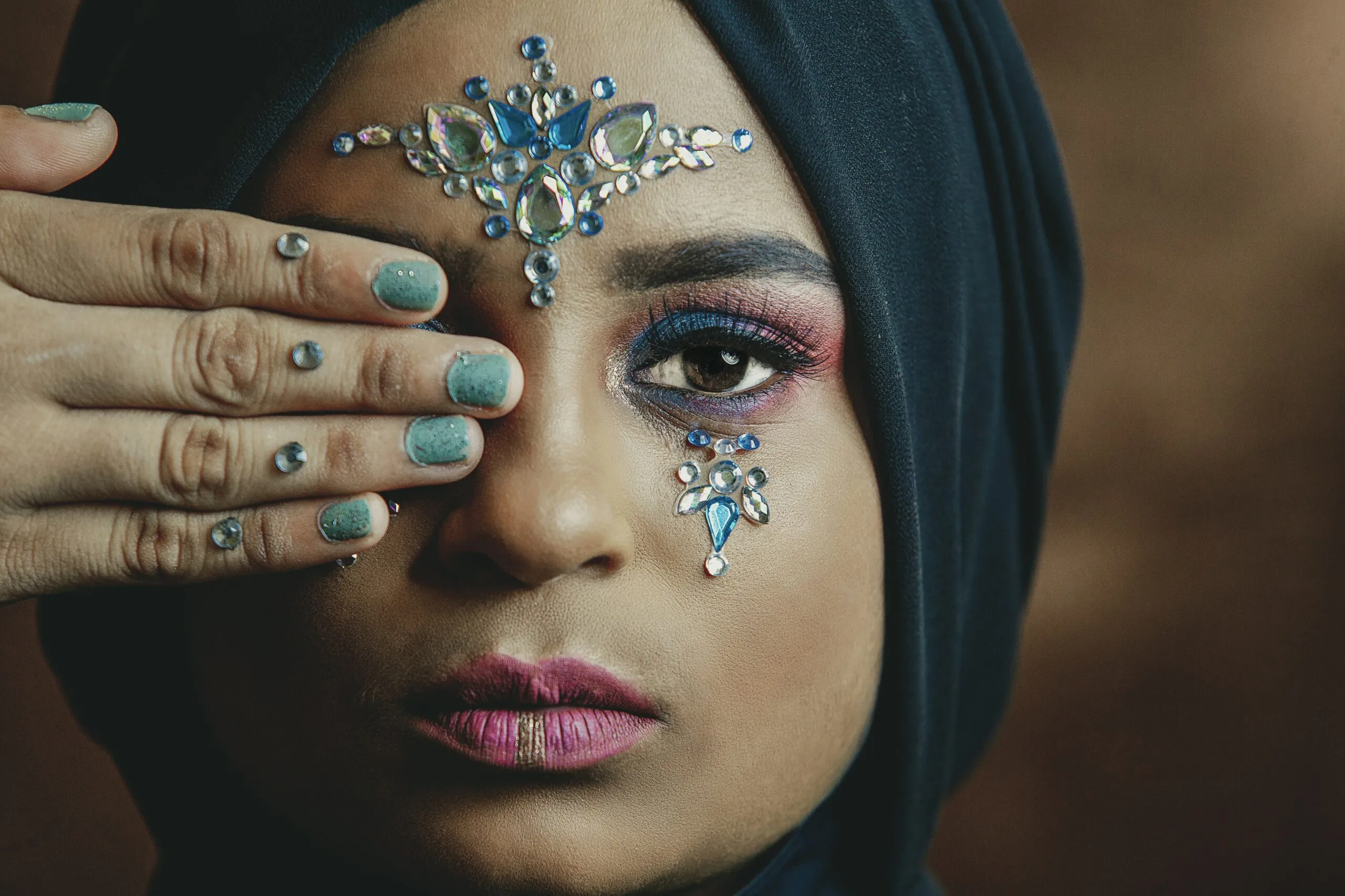 woman cover her right eye with her right hand and wearing blue hijab headdress
