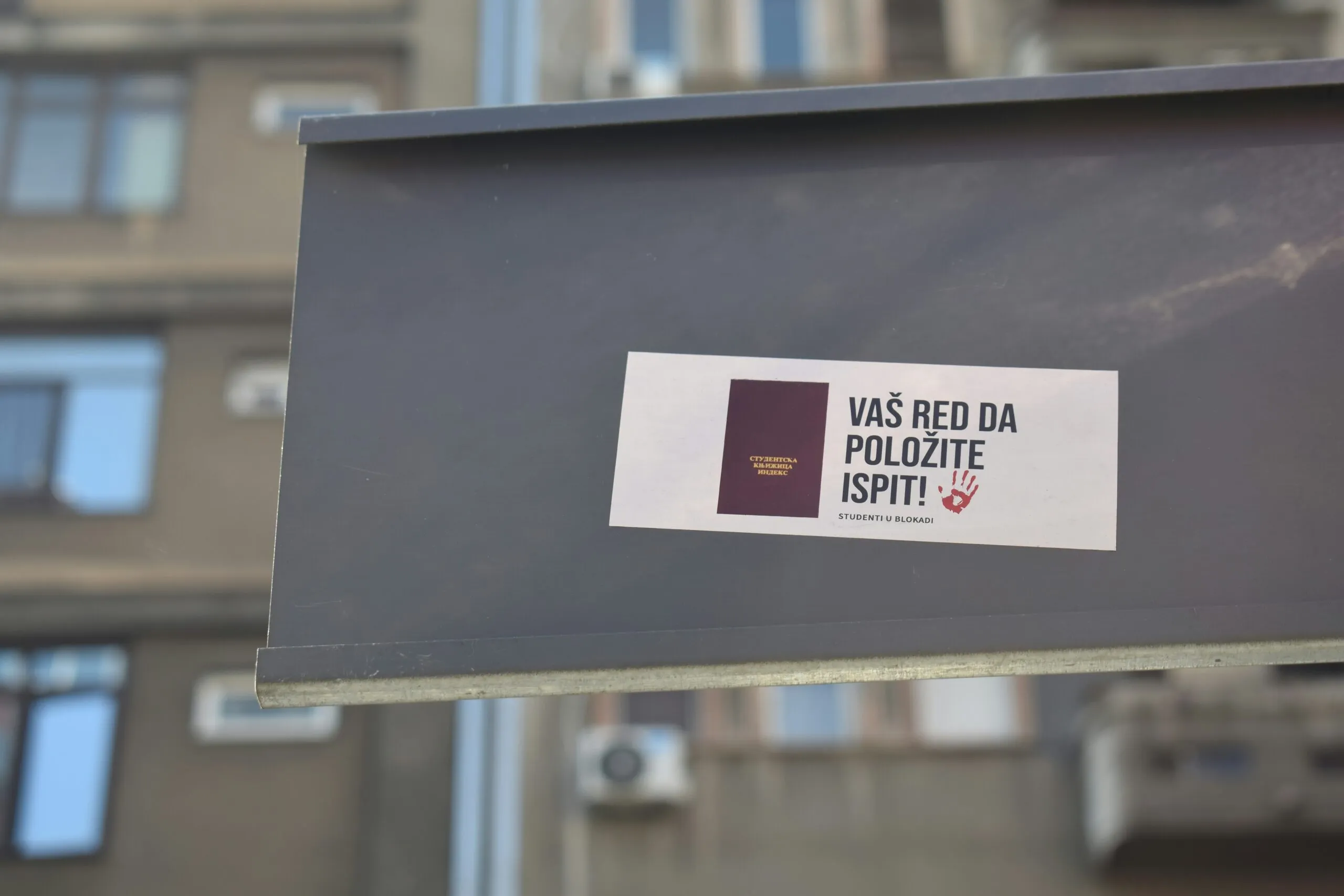 A sign with a sticker on it in front of a building