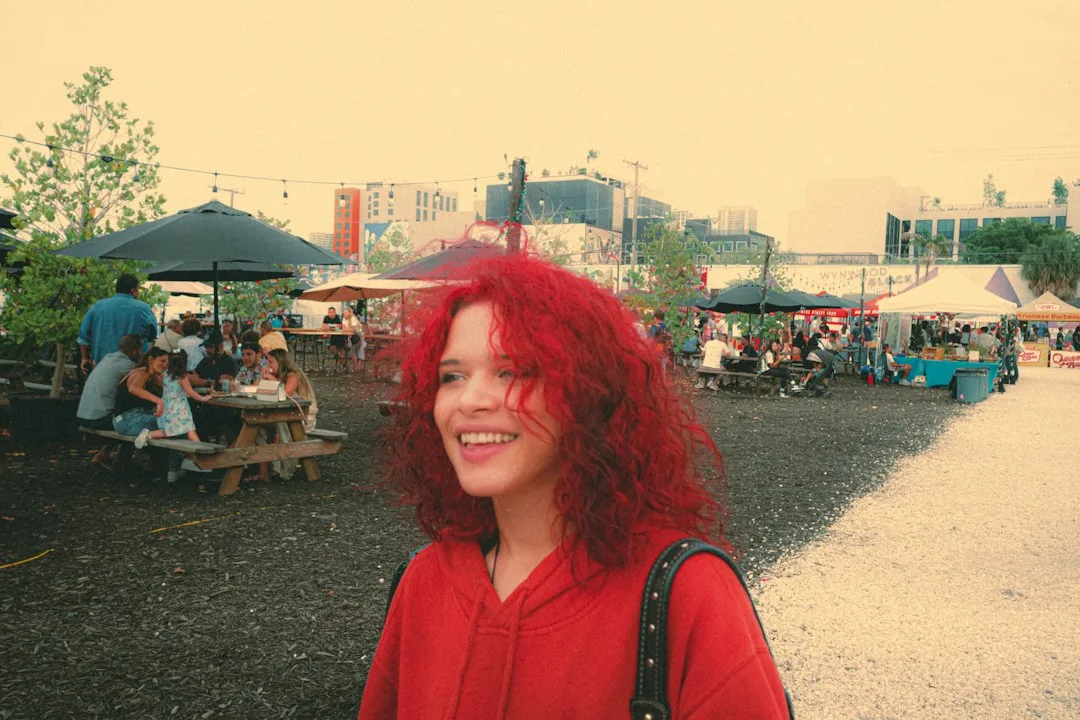 a woman with red hair standing in a park