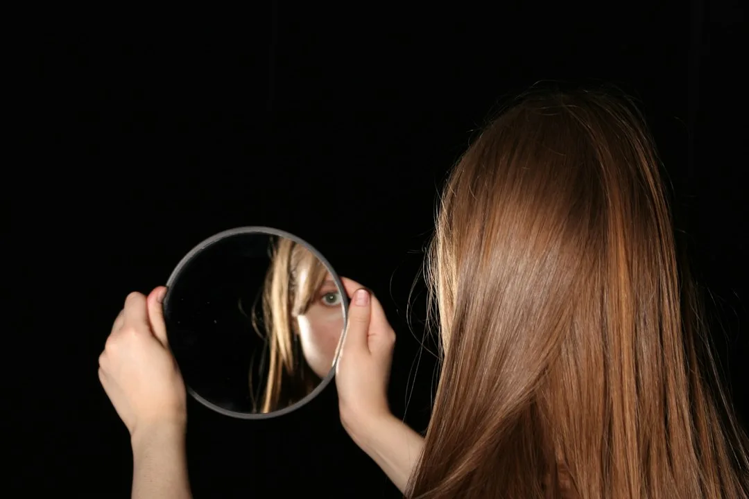 Woman looks at herself in a handheld mirror.