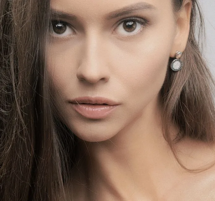 Close-up portrait of a woman with elegant earrings, showcasing natural beauty and subtle makeup.