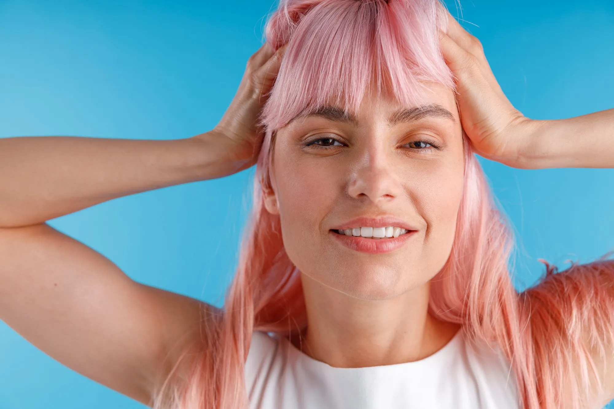 Close up portrait of beautiful female model with pink hair smiling at camera while posing isolated