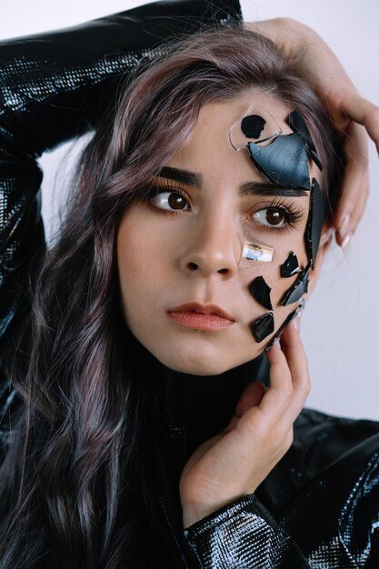 Close-up portrait of a young woman with broken glass on face