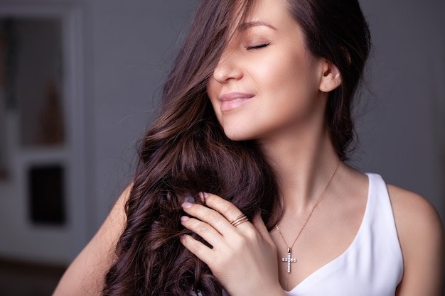 Closeup beautiful brunette girl with long hair in silver jewelry earrings, rings, bracelet, chain, necklace.