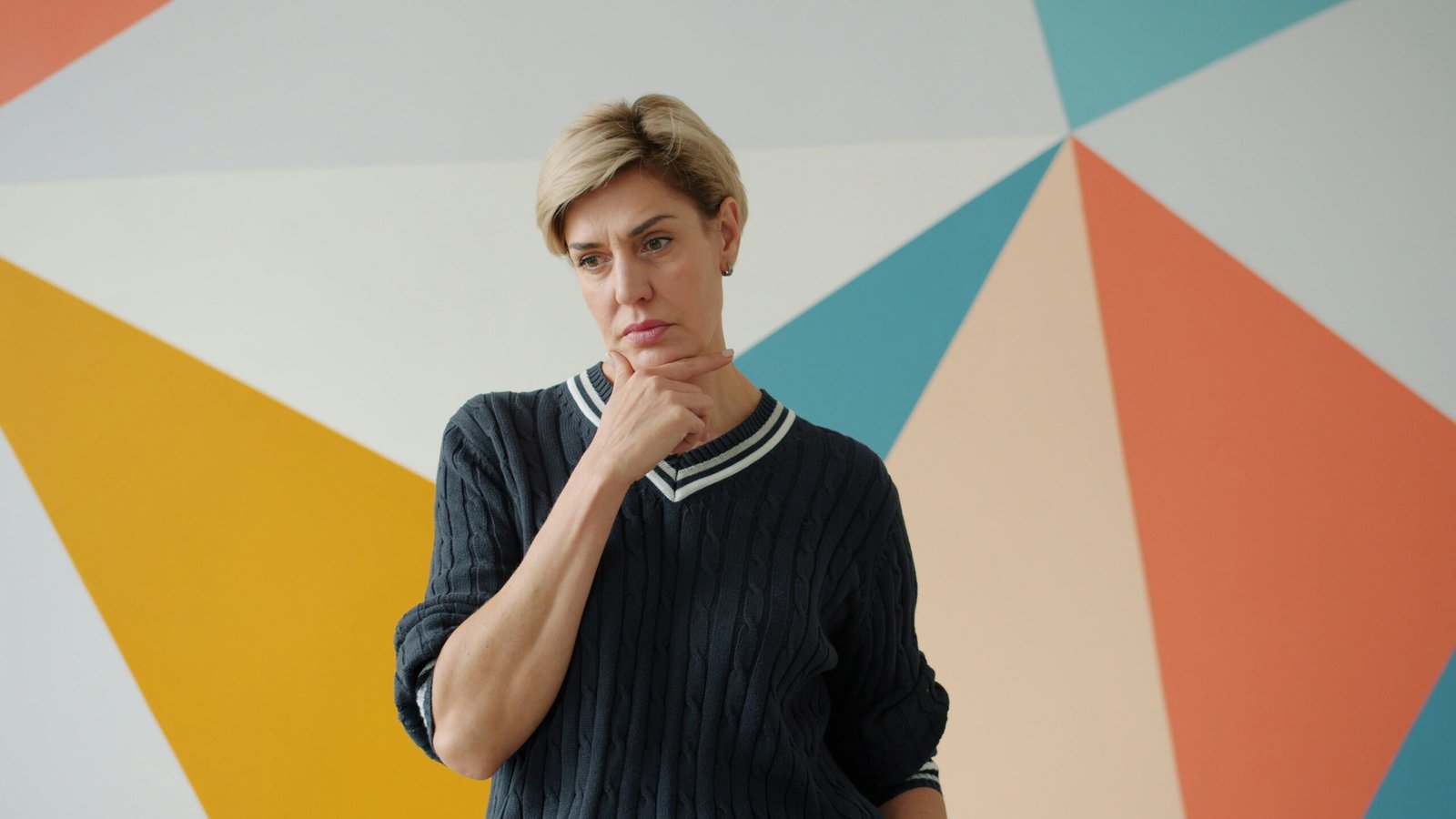 A woman with short blonde hair thinks.