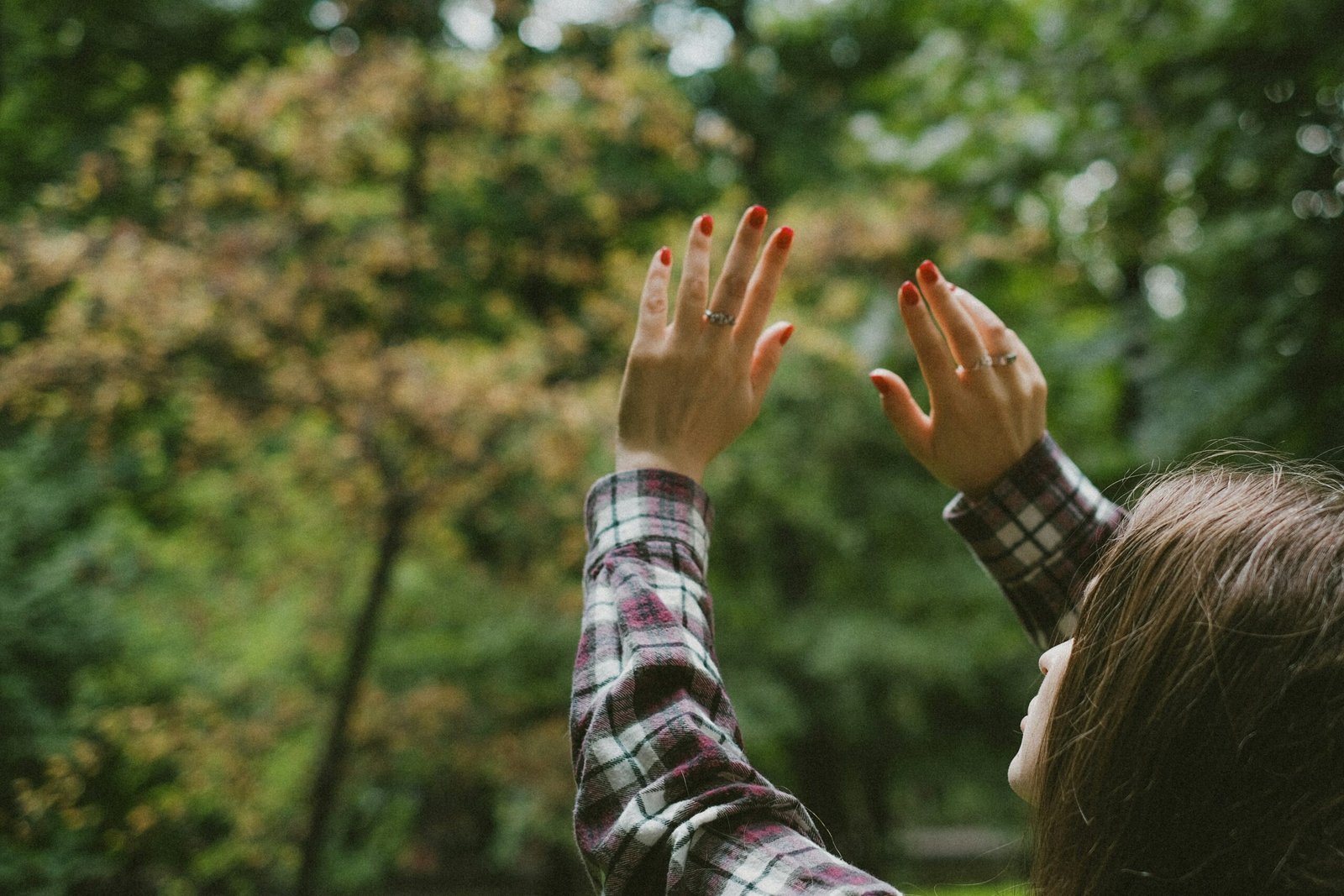 a woman reaching up to the sky with her hands