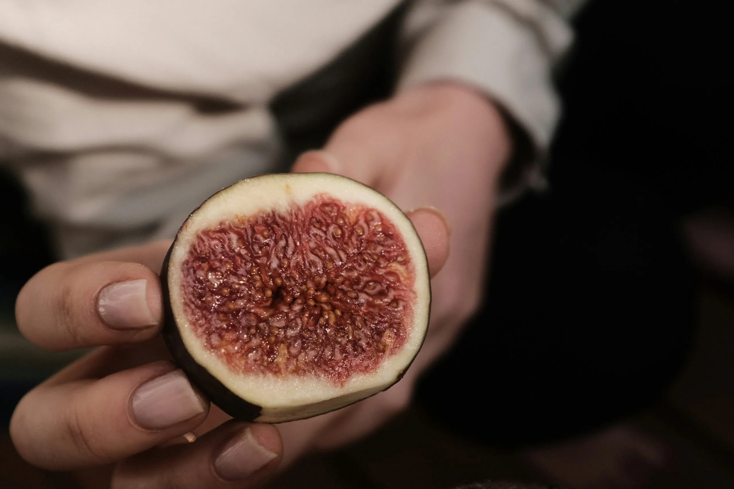 A person holding a piece of fruit in their hand