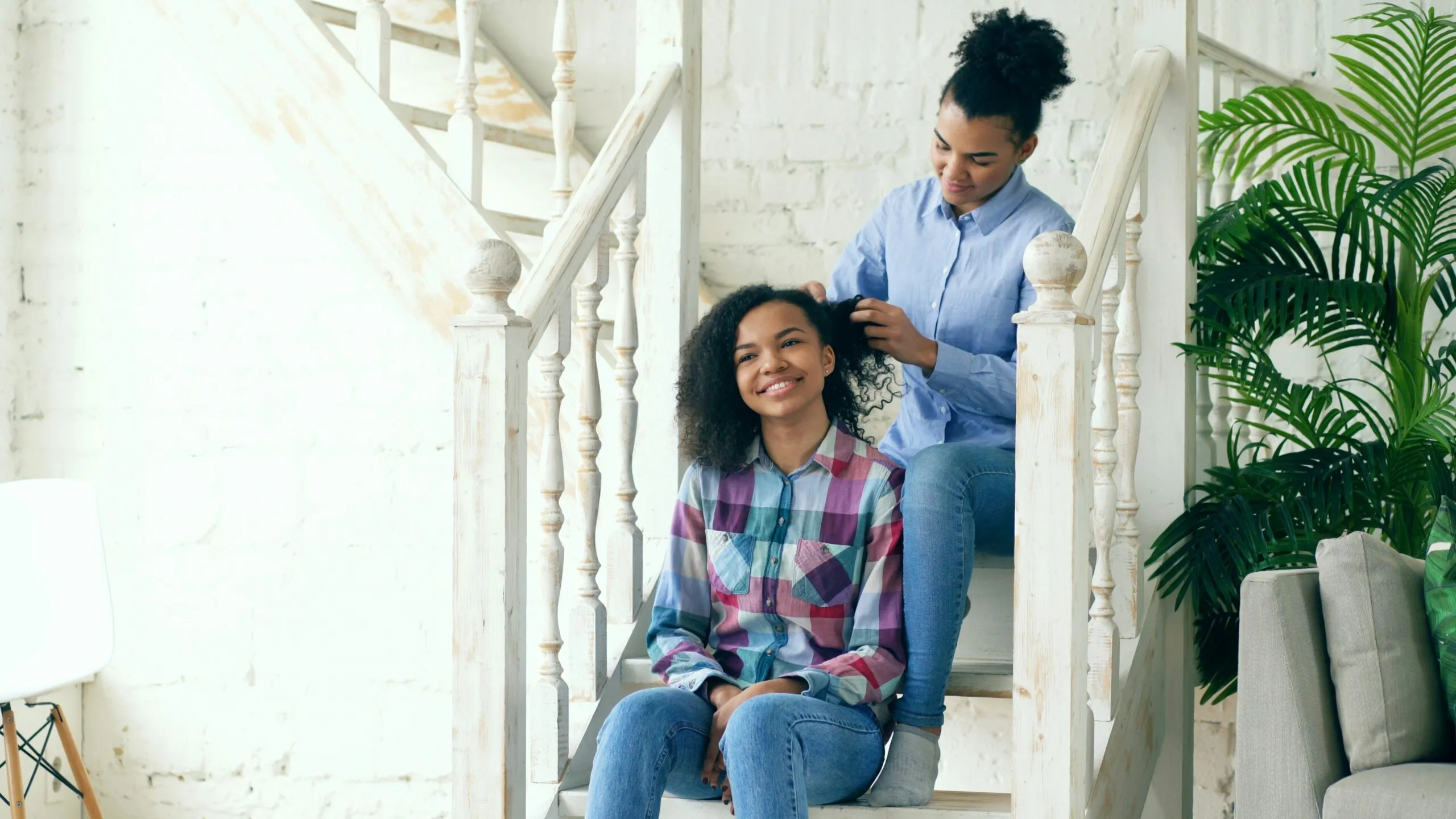 Mother braiding daughter's hair on staircase
