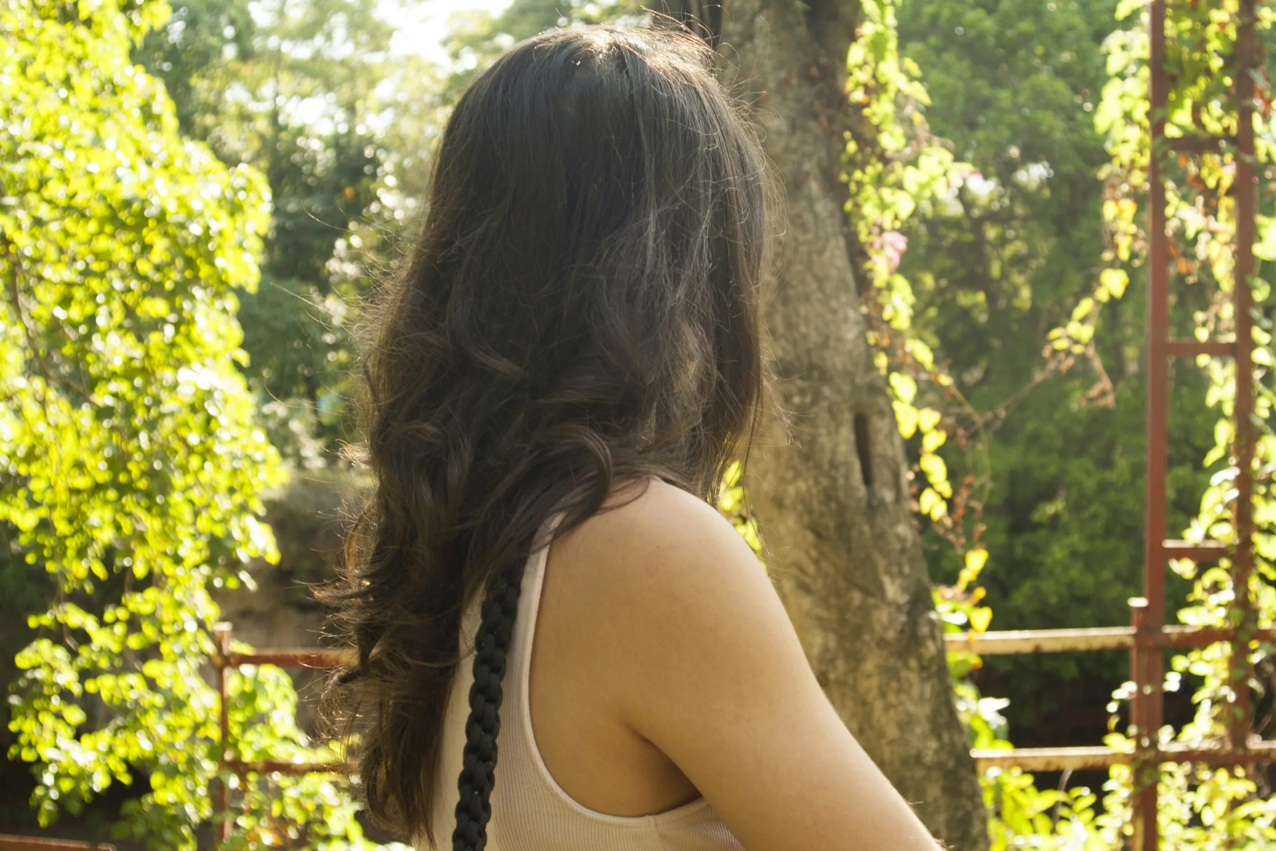 woman in black tank top standing near green trees during daytime