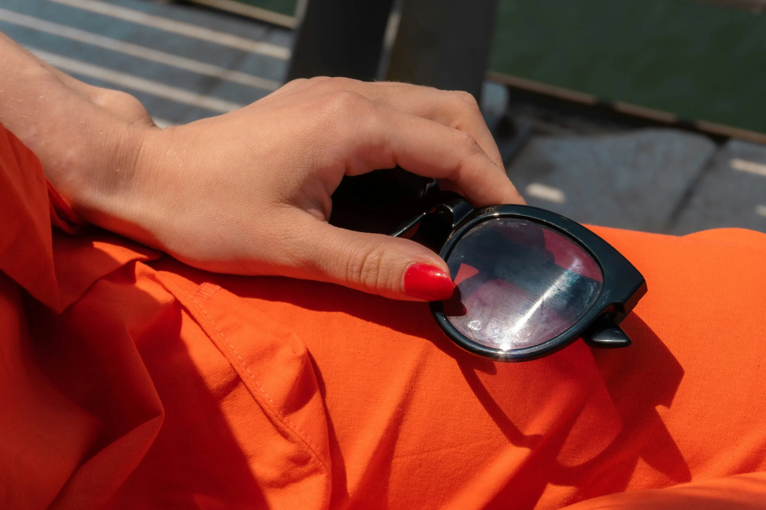 Woman's hand holding sunglasses on orange fabric