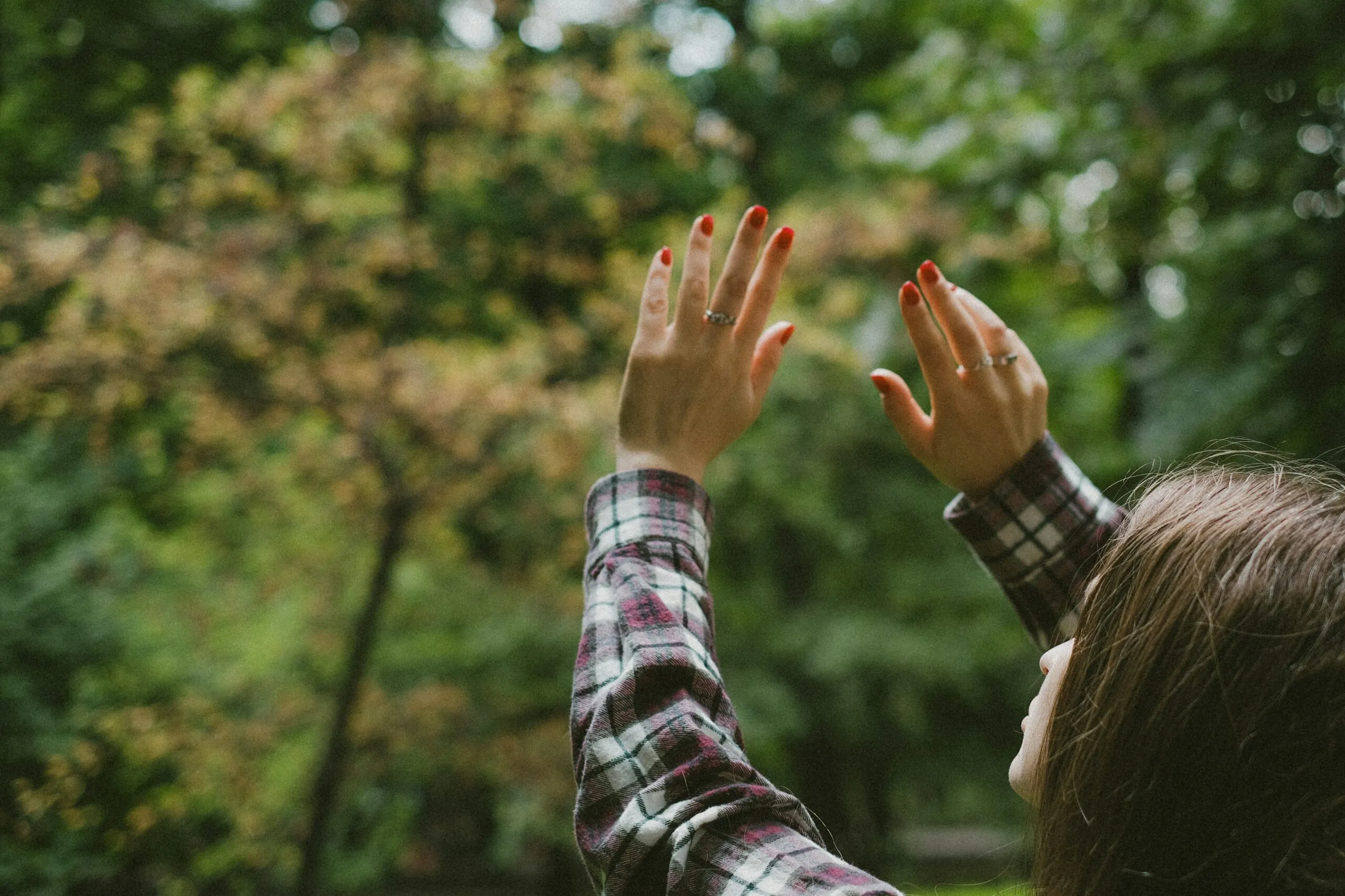 a woman reaching up to the sky with her hands