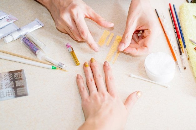 Professional manicurists do neil Art Glitter woman in a beauty salon