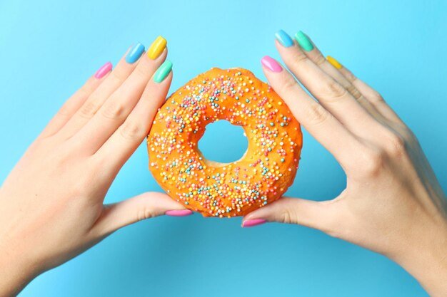 Woman holding delicious donut on color background