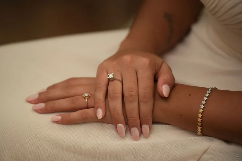 A close-up photo showcasing elegant manicured hands adorned with rings and a bracelet.