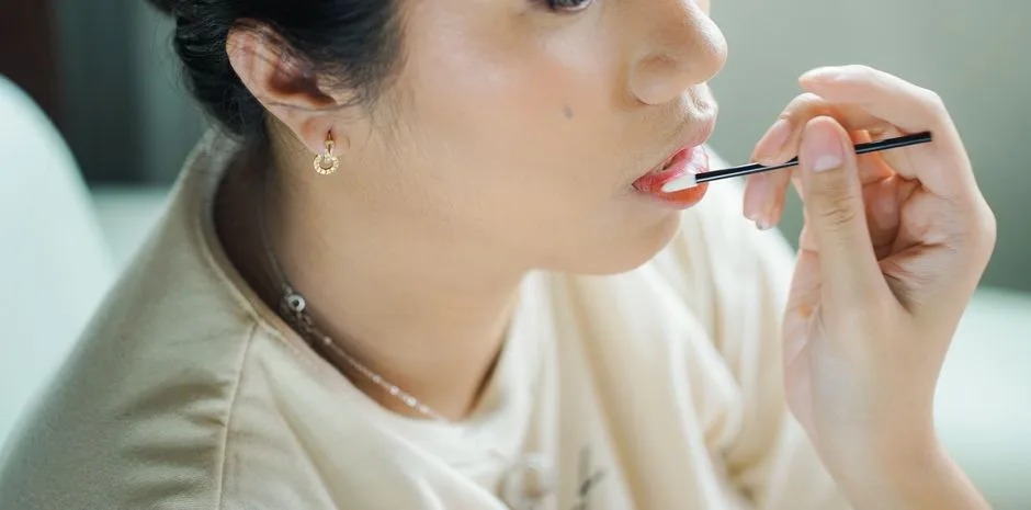 Close-up of a woman applying makeup with a brush, showcasing her lips.