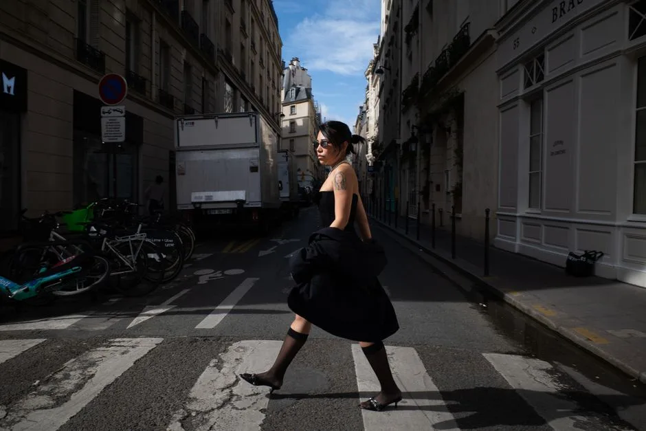 Fashionable woman walking across a Paris street, blending urban charm with elegance.