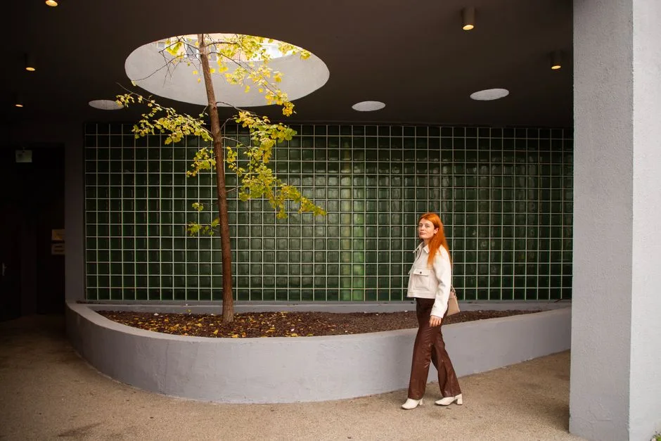 Stylish red-haired woman walking in a modern indoor area with geometric design in Istanbul.