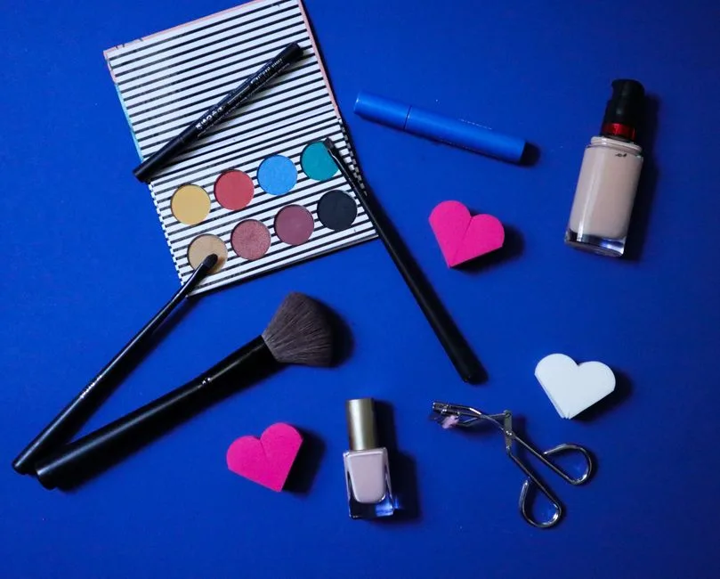 Colorful makeup products arranged stylishly on a blue backdrop for beauty inspiration.