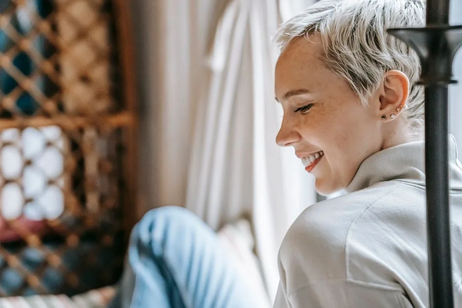 Back view of crop glad content female with trendy hairstyle smiling and looking down on blurred background