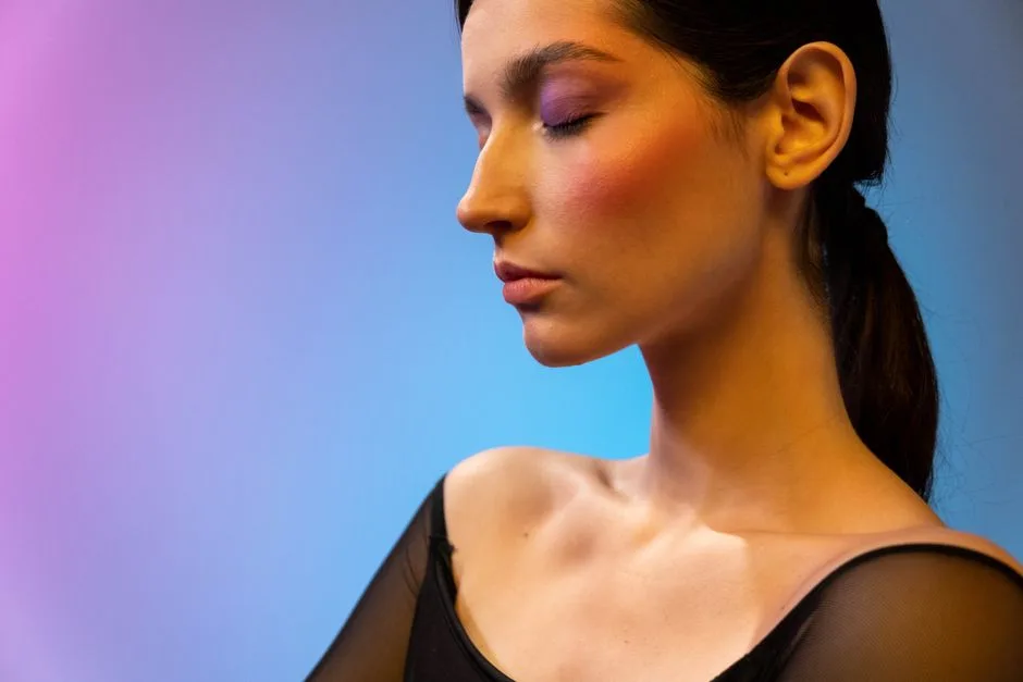 Portrait of an elegant woman with closed eyes, wearing makeup against a colorful gradient background.
