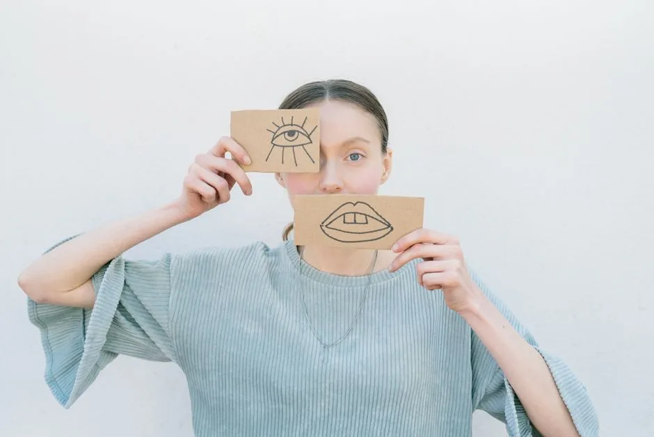 Woman holding cardboard drawings of an eye and mouth, creating an artistic portrait.