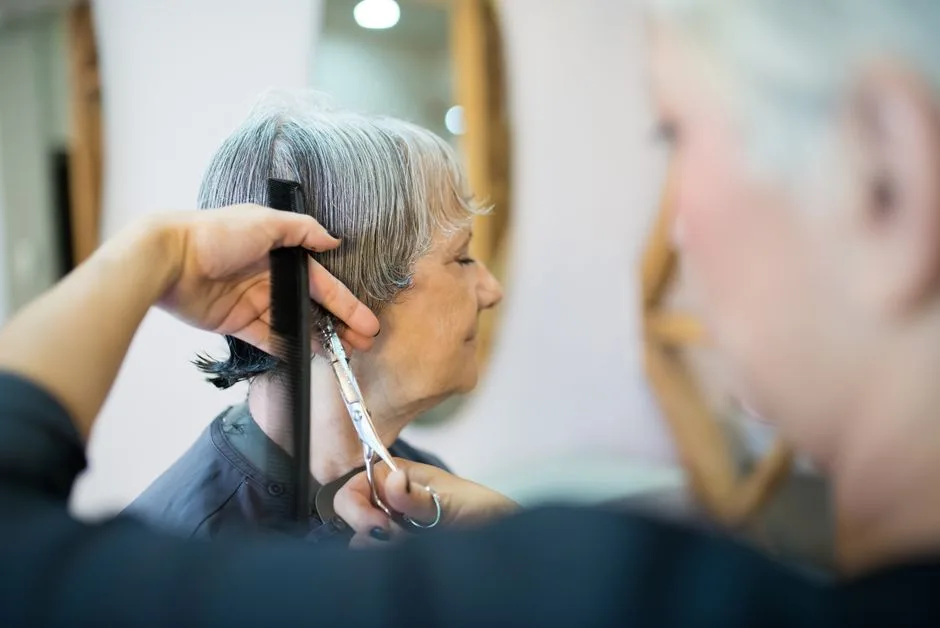 Elderly woman receiving a haircut in a trendy Portuguese hair salon.
