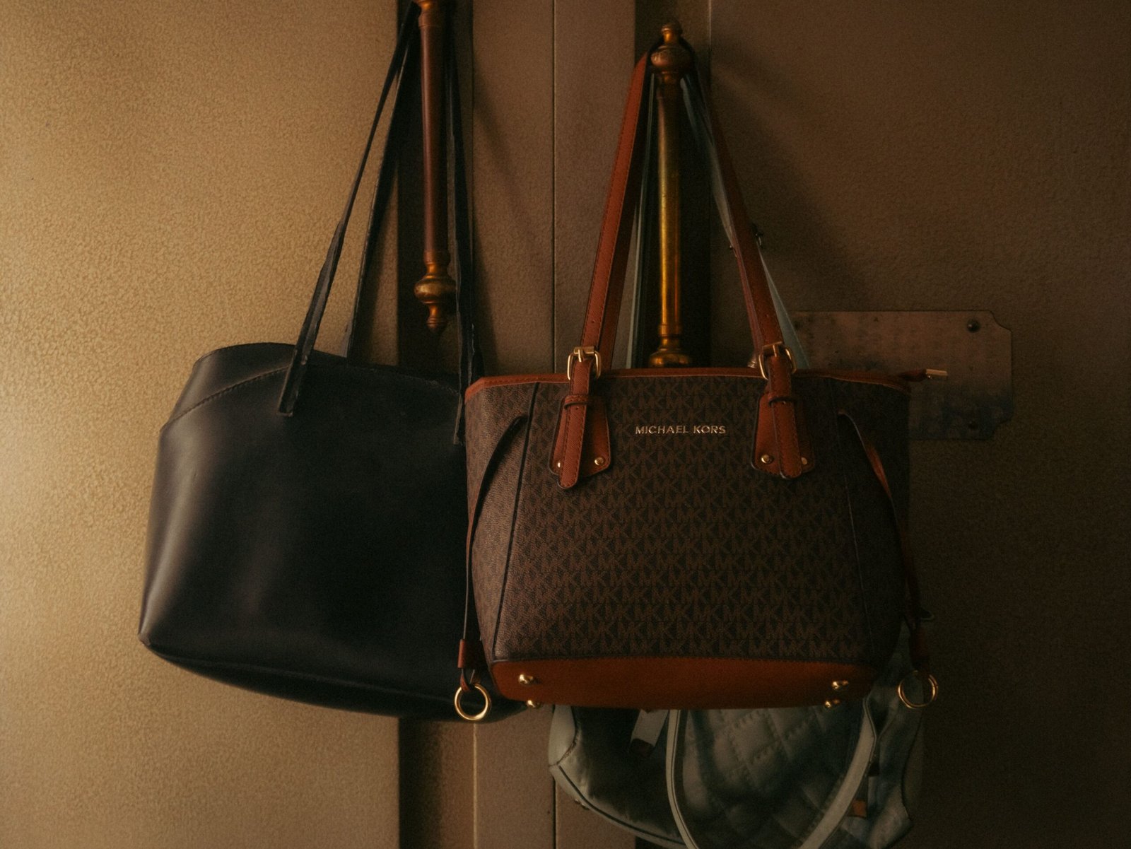 Stylish leather handbags hanging on a wall hook, showcasing elegant design and rich tones.