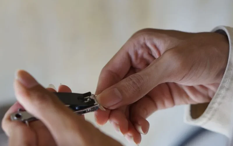 A detailed view of hands using nail clippers for personal grooming. Focus on hygiene and care.