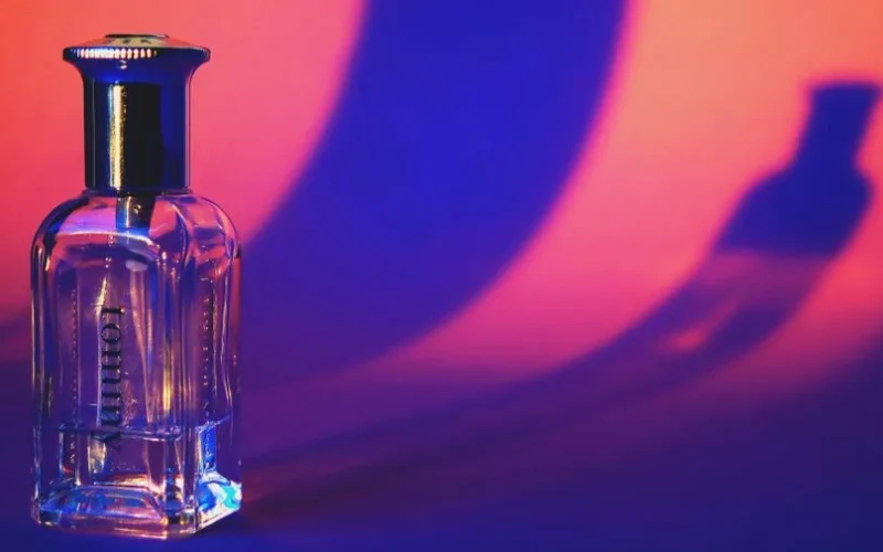 A glass perfume bottle casting vibrant shadows in a colorful setting.