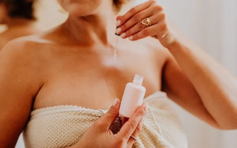 Close-up of a woman applying serum to her skin, enhancing beauty routine.