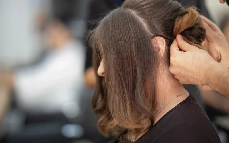 Close-up of a hairstylist creating an elegant hairstyle for a woman in a salon.