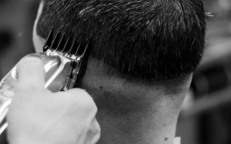 Close-up of a barber giving a haircut with clippers in a classic black and white theme.