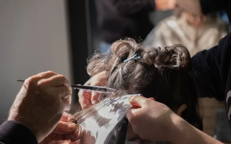 Hairdresser applying foil highlights to client's hair in a salon.