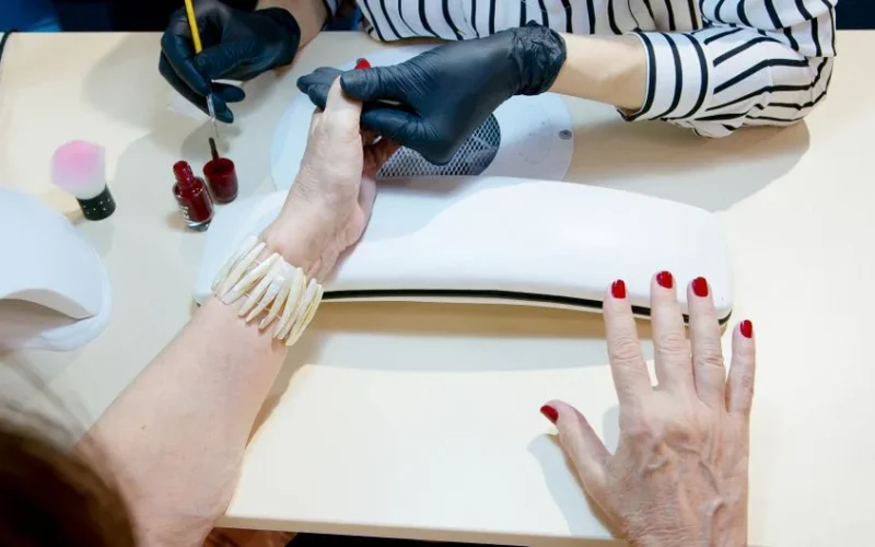 Top view of a professional manicure session with red nail polish application in a modern salon.