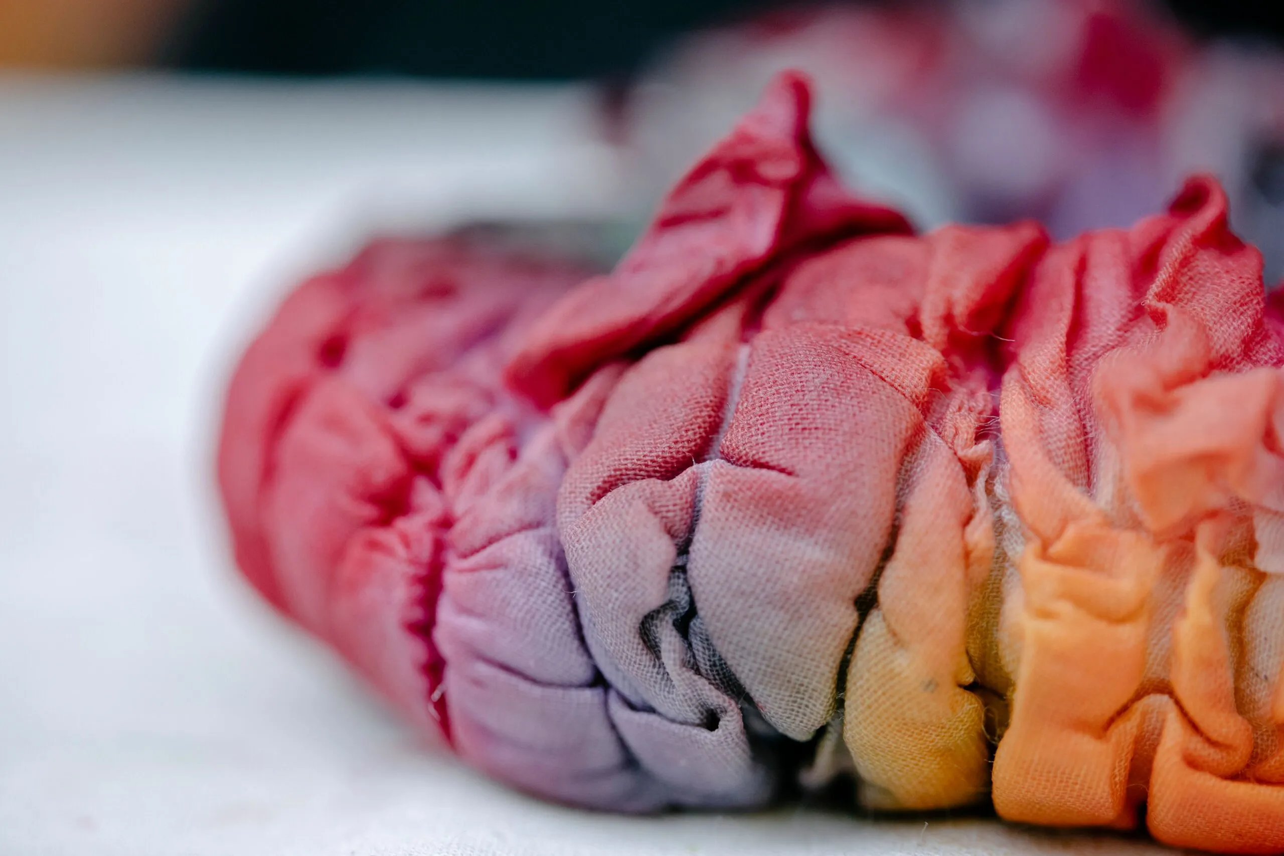 Focused shot of colorful, creased tie-dye fabric, showcasing its vibrant spectrum and texture.