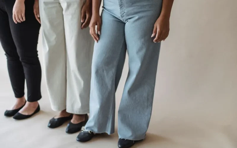 Three women standing in stylish pants showcasing diverse fashion on a neutral background.
