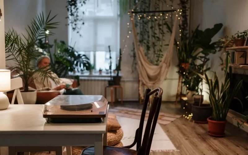 A cozy living room with plants, a hammock, and a vintage turntable, perfect for relaxation.