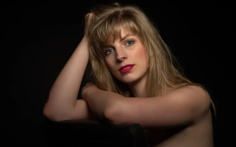 Captivating portrait of a blonde woman with a black background, showcasing elegance and beauty.