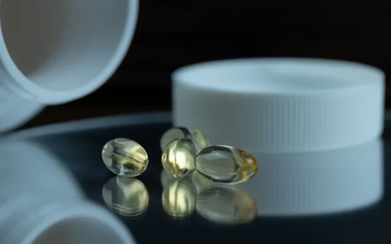 Focused image of gel capsules with a white bottle cap, emphasizing health and supplements.