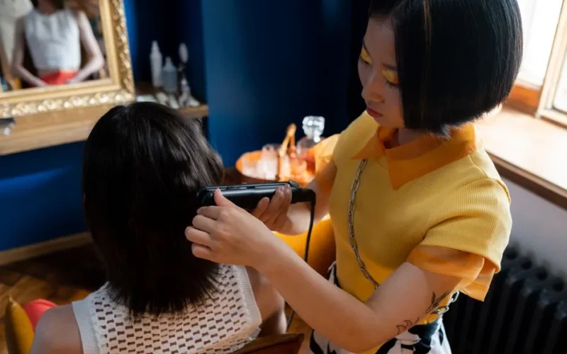 A hairdresser styles a client's hair with a straightener in a modern salon setting.