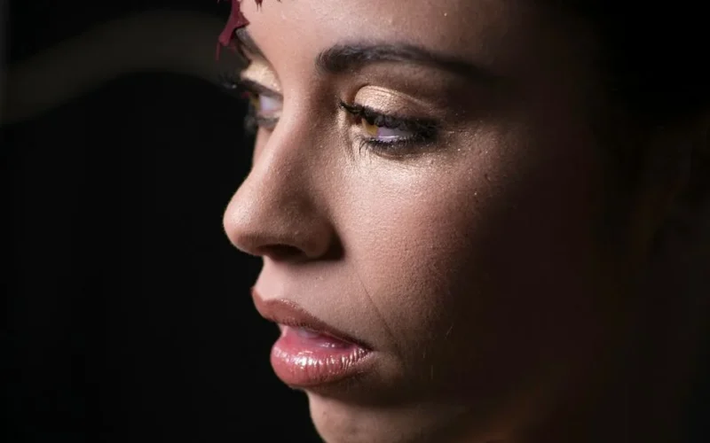 Elegant close-up portrait of a woman with glitter makeup in a studio setting.