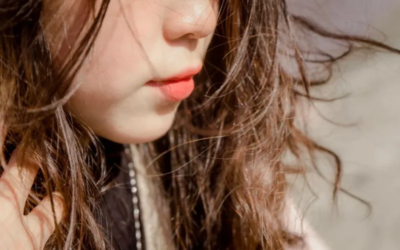 A detailed close-up of a woman with flowing hair and natural beauty, showcasing vibrant lips and skin.
